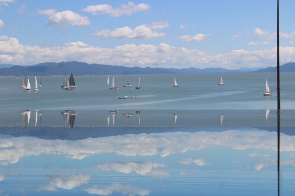 Veleiros aguardando a largada. Capturei o reflexo dos veleiros no vidro da nossa janela, criando essa imagem invertida na foto. 